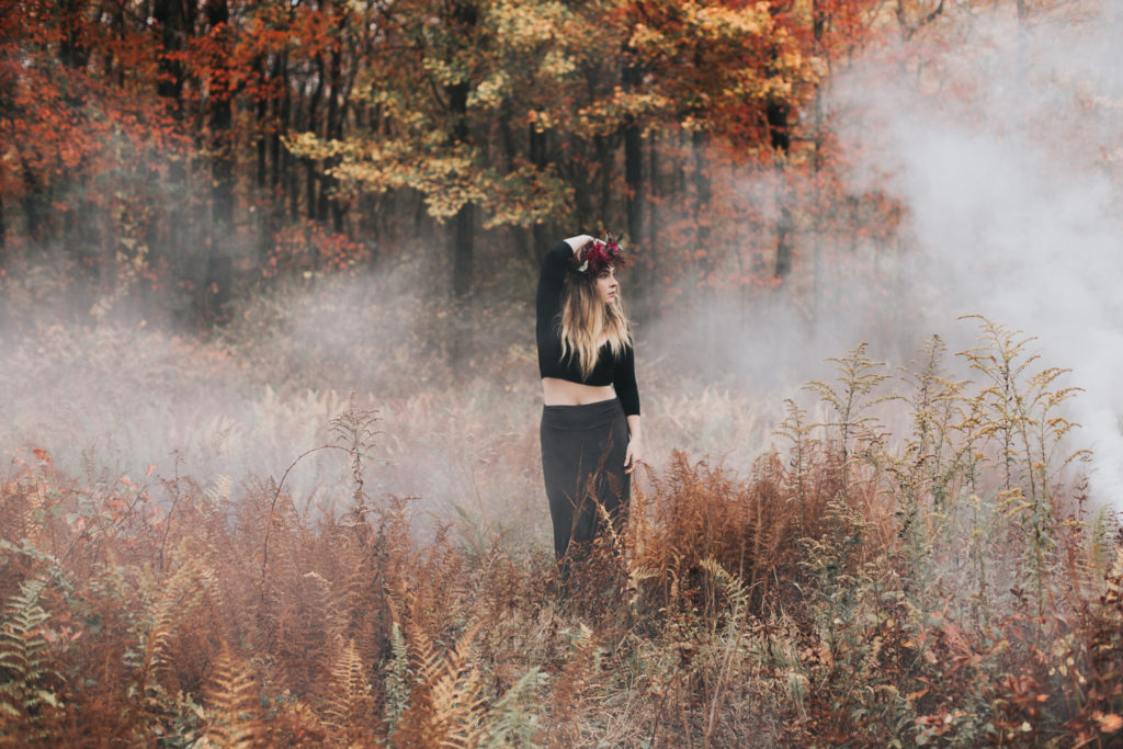 portrait of a girl in black dress during the fall with smoke bomb effect in background