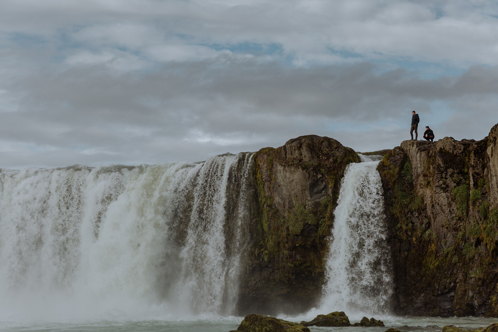 two men standing at the top of godafoss waterfall in iceland