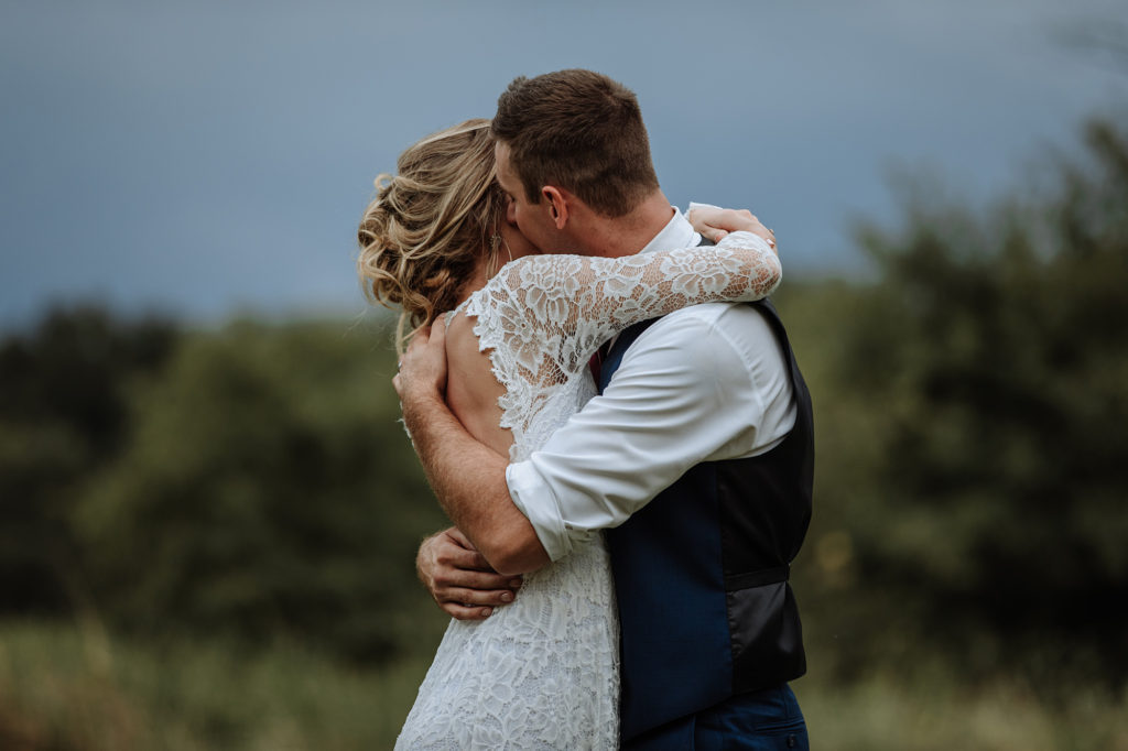 newly married bride and groom hugging in a field