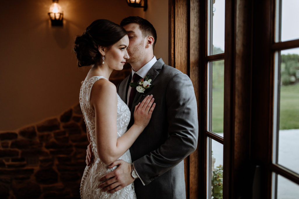 bride and groom standing in front of door with window light