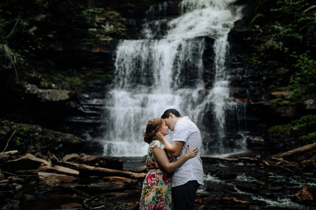 couple kissing in front of a waterfall