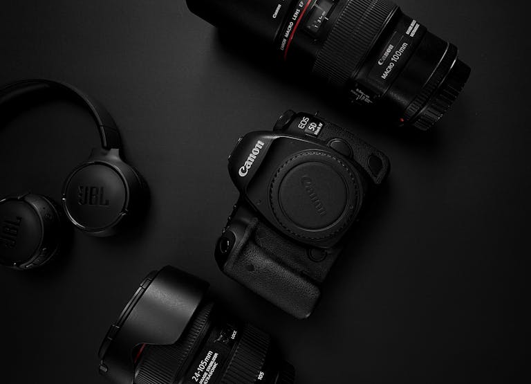 A stylish flat lay showcasing camera and audio gear on a dark background.