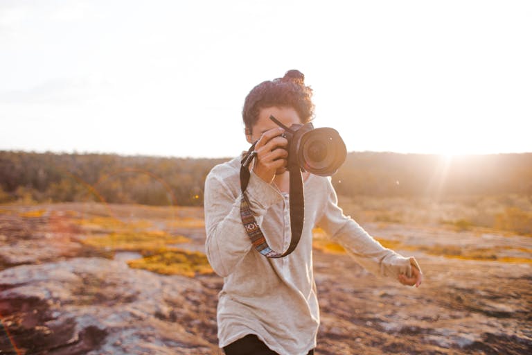 An outdoor photographer captures the sunset with a camera, surrounded by nature's beauty.
