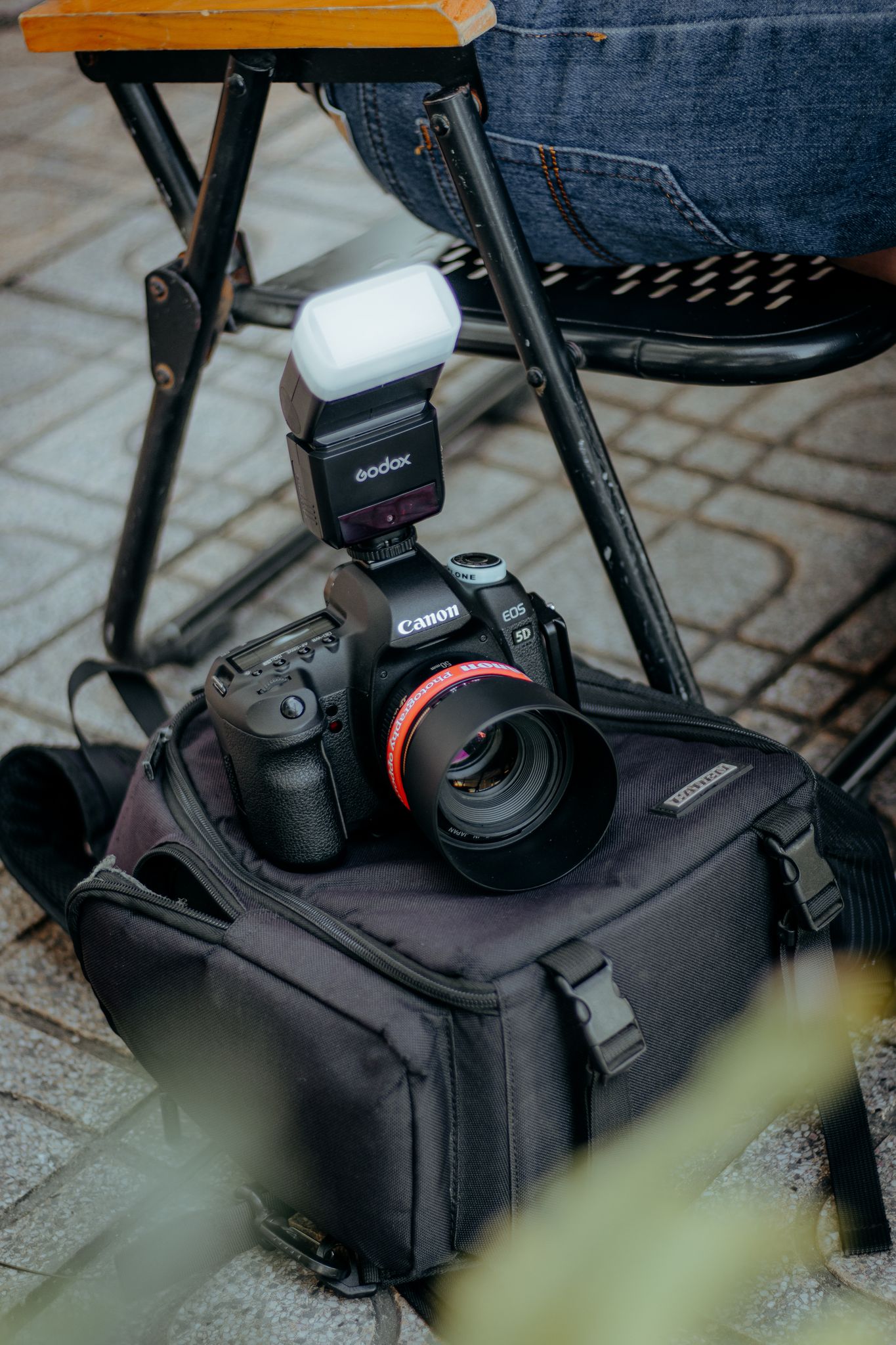 Camera with flash setup resting on a bag outdoors, ready for photography.