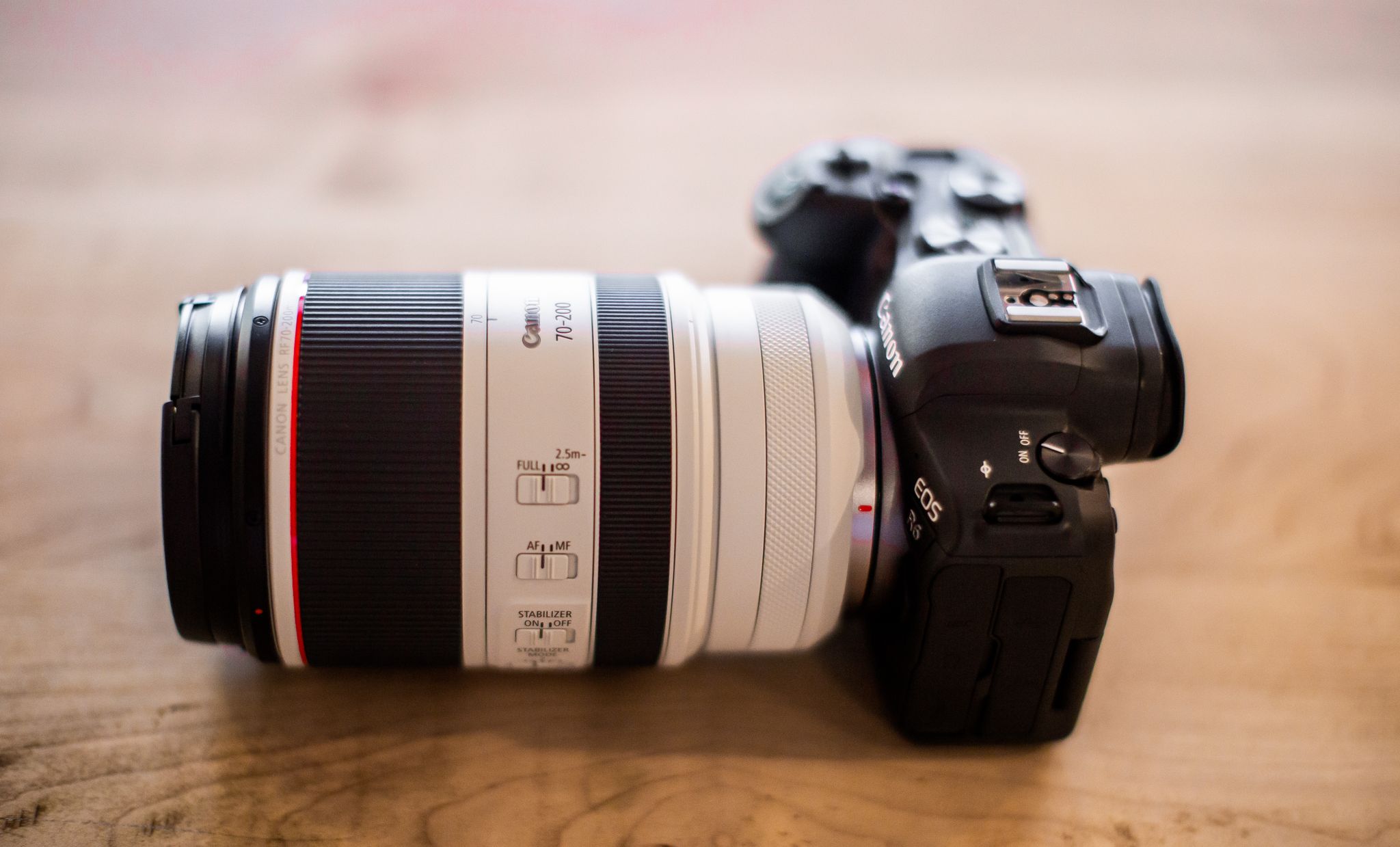 Close-up of a DSLR camera with a telephoto lens on a wooden surface.