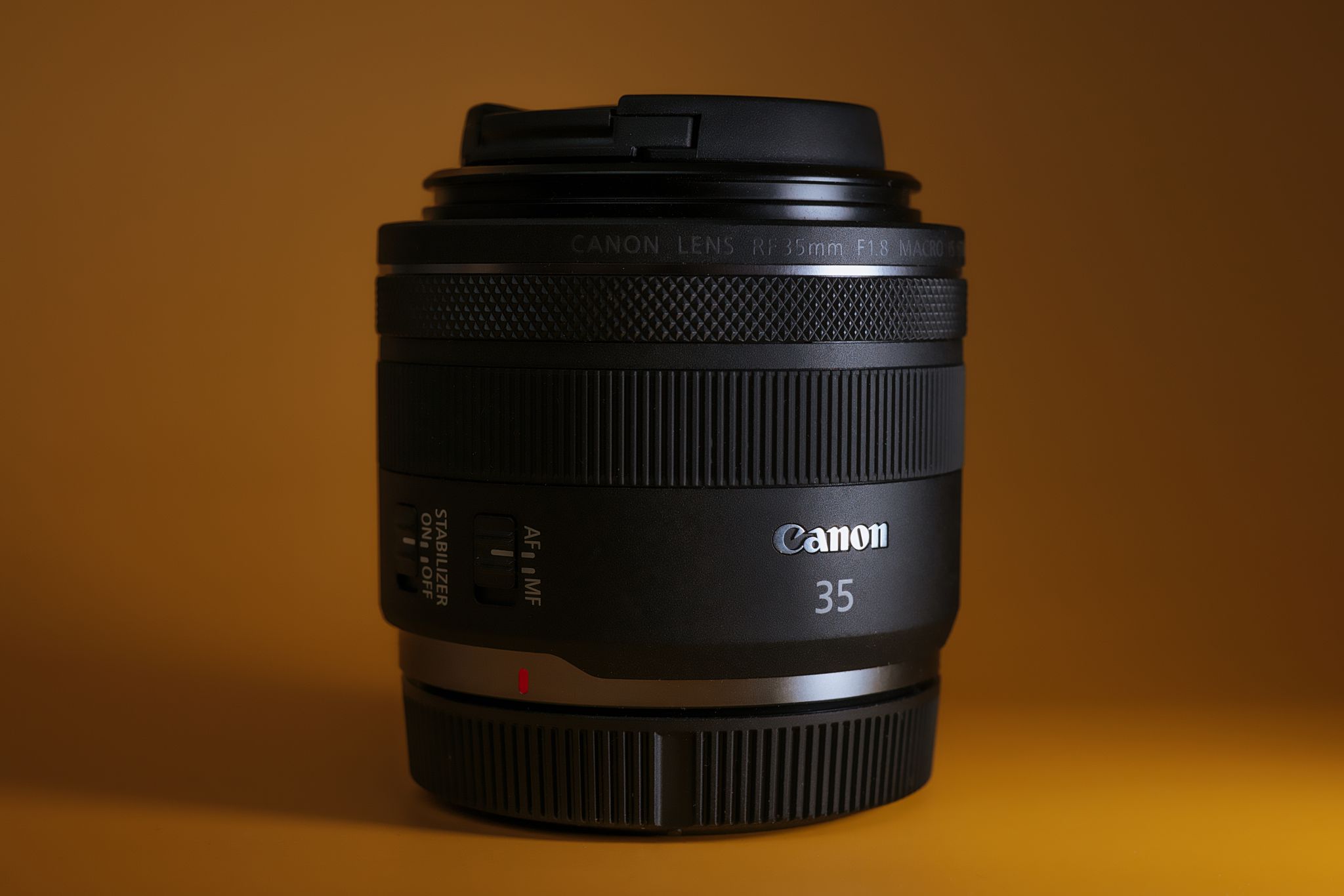 Detailed close-up of a camera lens with yellow background, showcasing lens specifications and design.